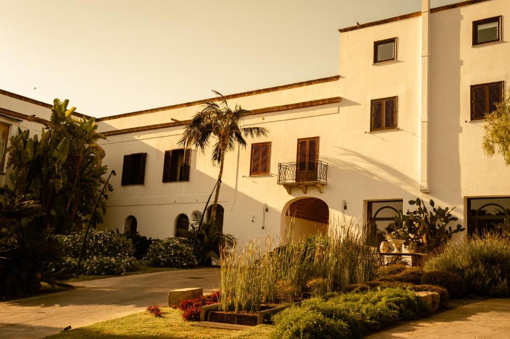 un grand bâtiment blanc avec un palmier en face dans l'établissement Villa Favorita Hotel & Events, à Marsala