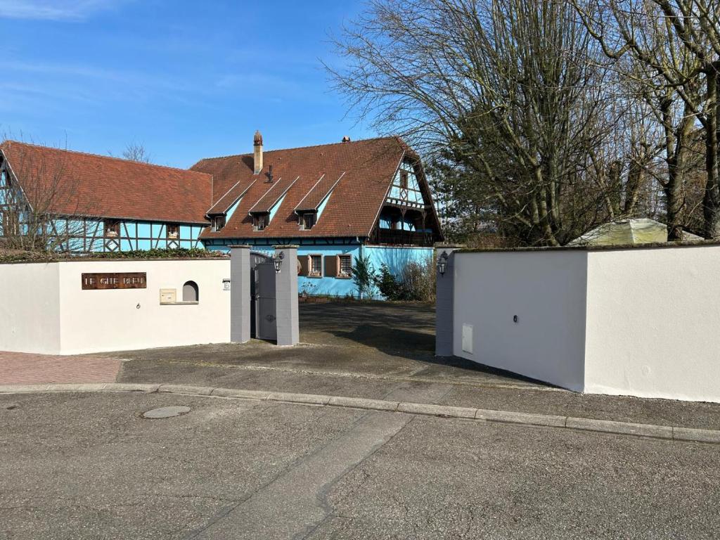a white building with a gate and a house at Le Gîte bleu in Willgottheim
