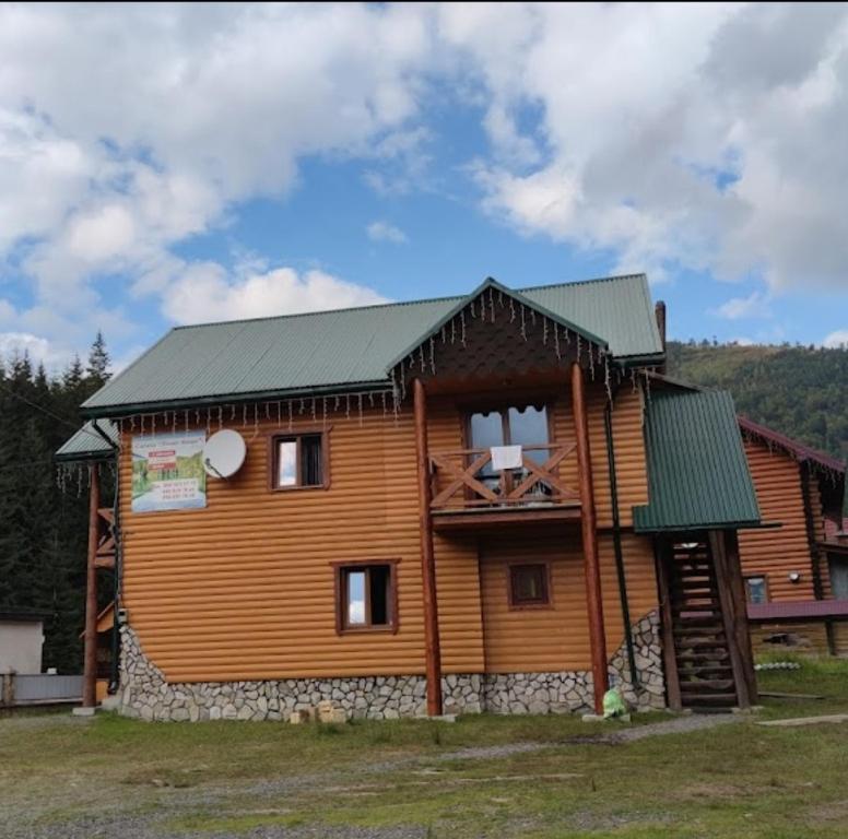 ein Blockhaus mit grünem Dach in der Unterkunft Апартаменти Лісова тиша in Synewyrska Poljana