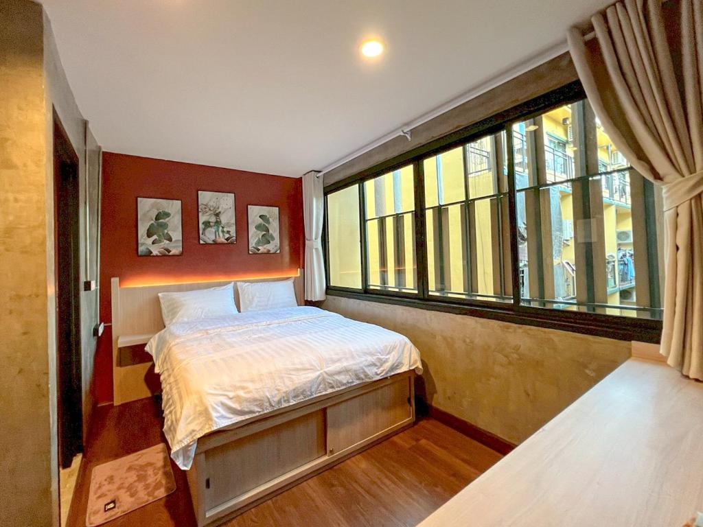 een slaapkamer met een bed en een groot raam bij Wat We See Hostel in Khlong San