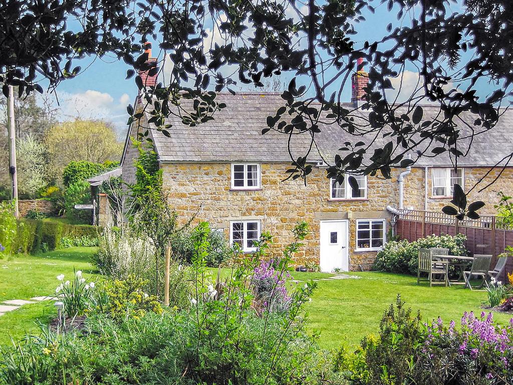 a brick house with a garden in front of it at Barters Cottage in Chideock