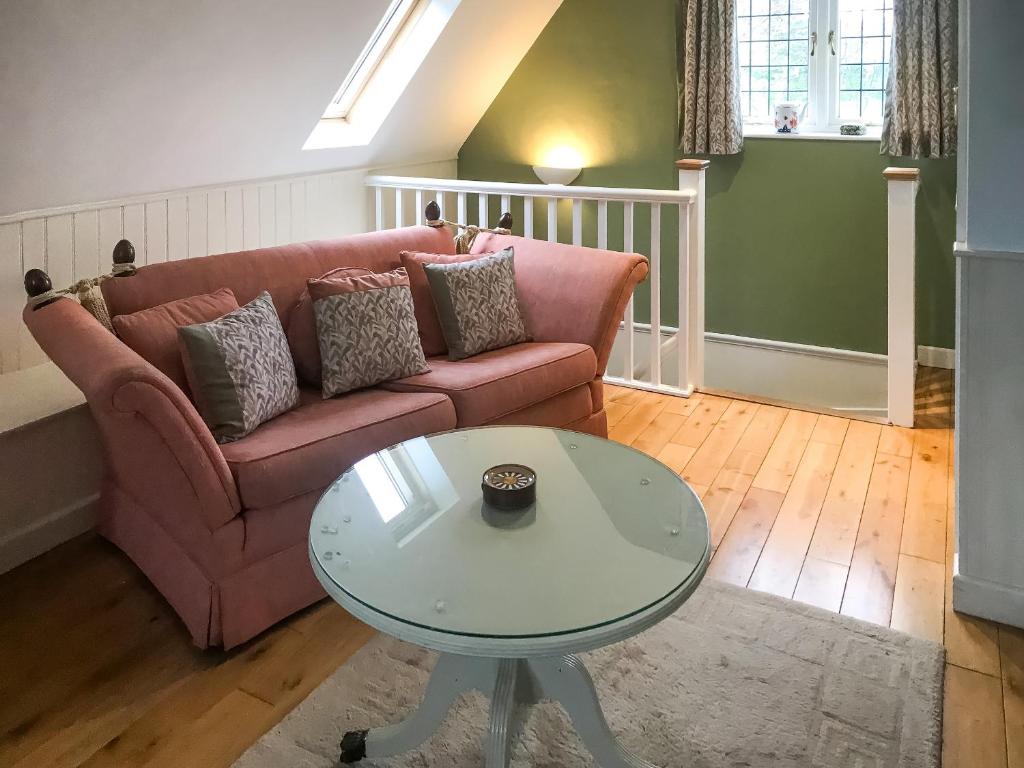 a living room with a pink couch and a table at Goodwood Coach House in Westhampnett