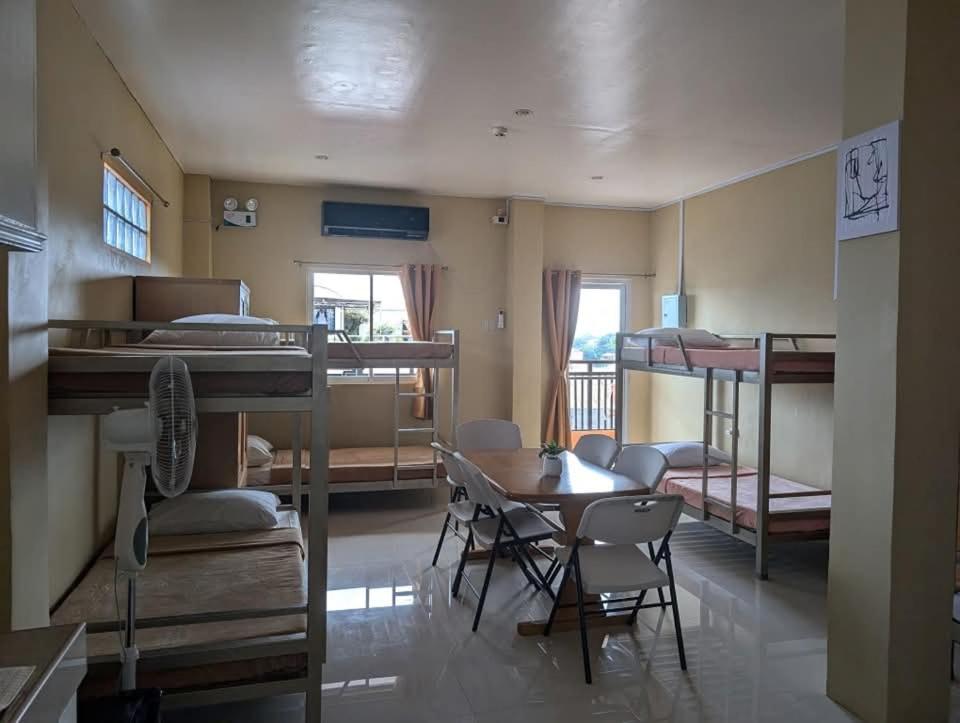 a room with several bunk beds and a table and chairs at L'islo INN in Davao City