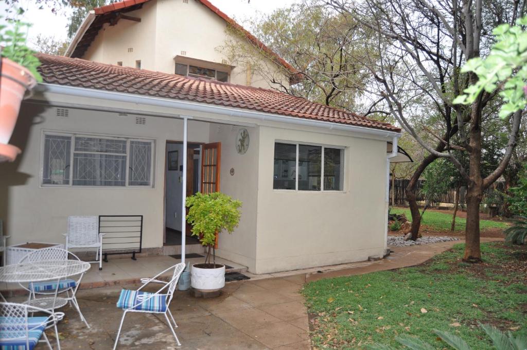 a small white house with chairs and a table at Cottage Glen Lorne in Gaborone