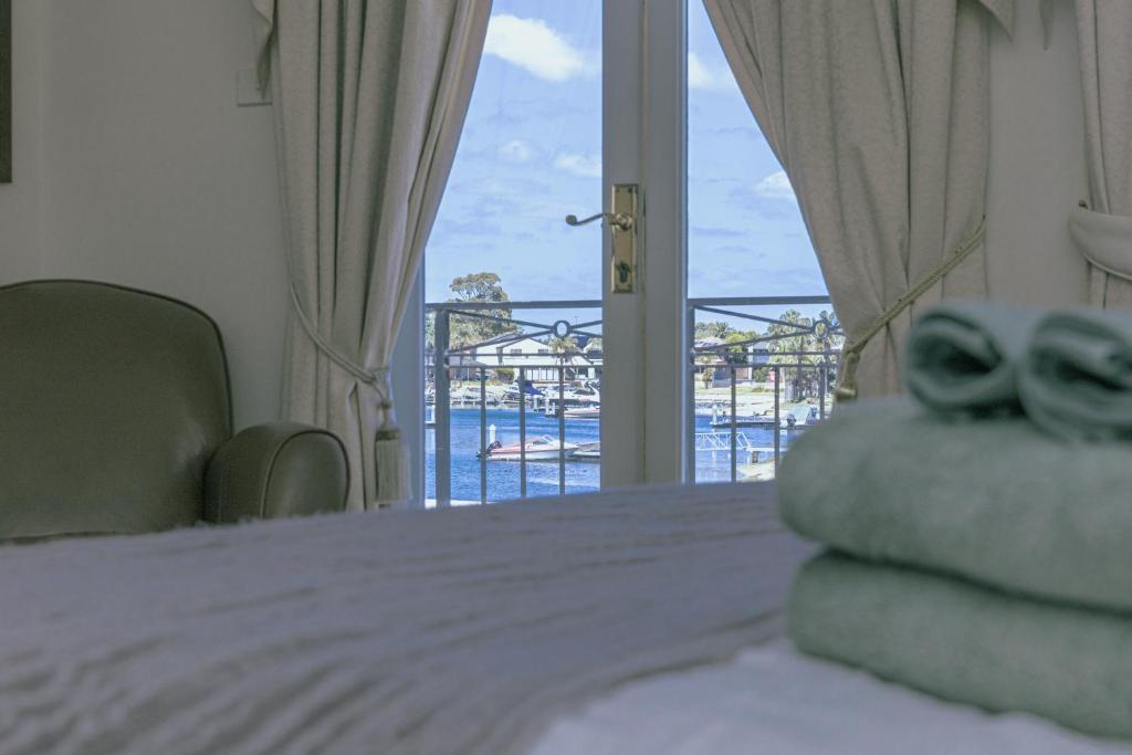 Un dormitorio con una cama con vista a un balcón. en Puddings Home mooring and waterfront getaway, en Patterson Lakes