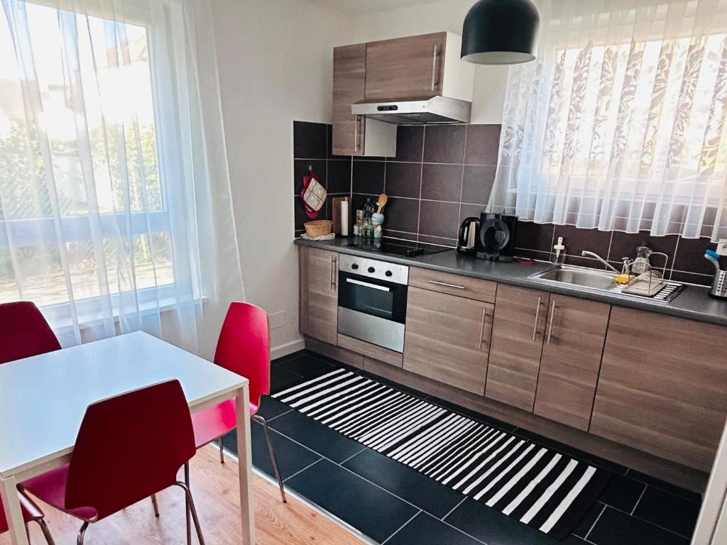 a kitchen with a table and red chairs at Charmant Studio proche tramway in Strasbourg