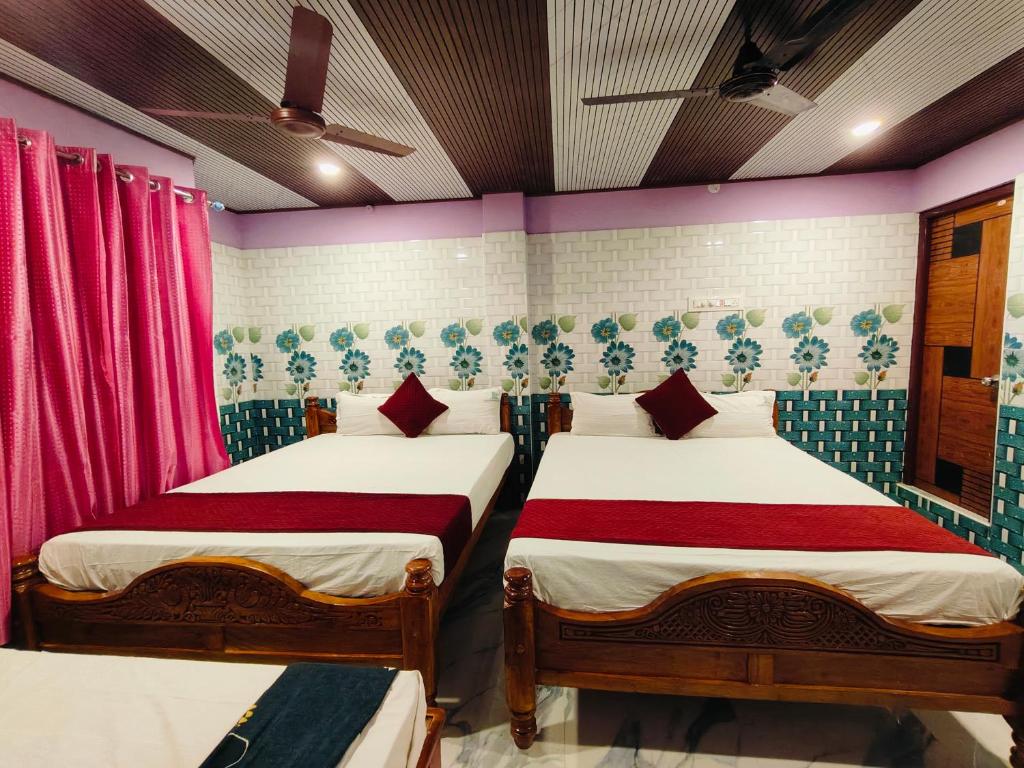 two beds in a room with pink and blue at THIRUNALLAR Udhayam Residency INN in Thirunallar