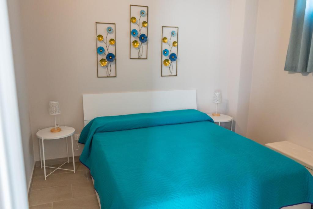 a bedroom with a blue bed and three pictures on the wall at Casetta Giardinetto in Altavilla Milicia
