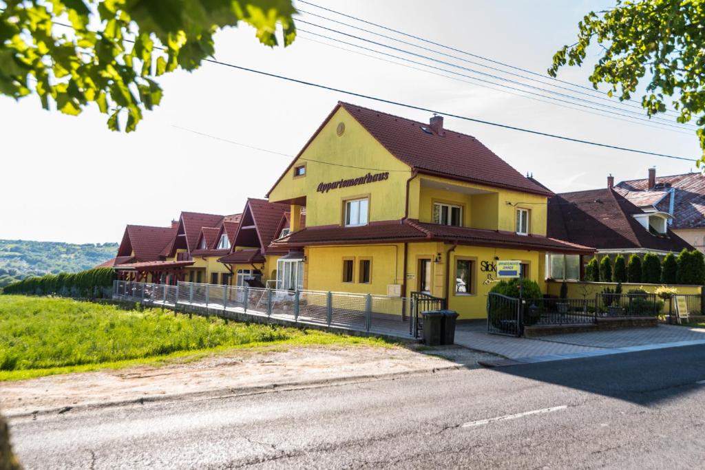 une maison jaune sur le côté d'une route dans l'établissement Nemes Apartmanház, à Hévíz