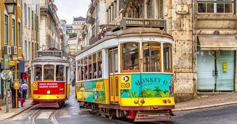 two trolley cars driving down a city street at Ap Cristo in Sobreda