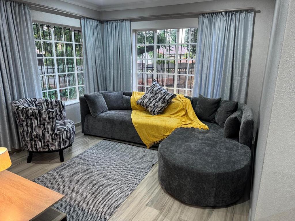 a living room with a couch and a chair at ORT Tranquil Stay in Boksburg