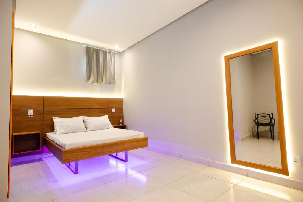 a small bedroom with a bed and a mirror at Pousada Malibu in Vitória da Conquista