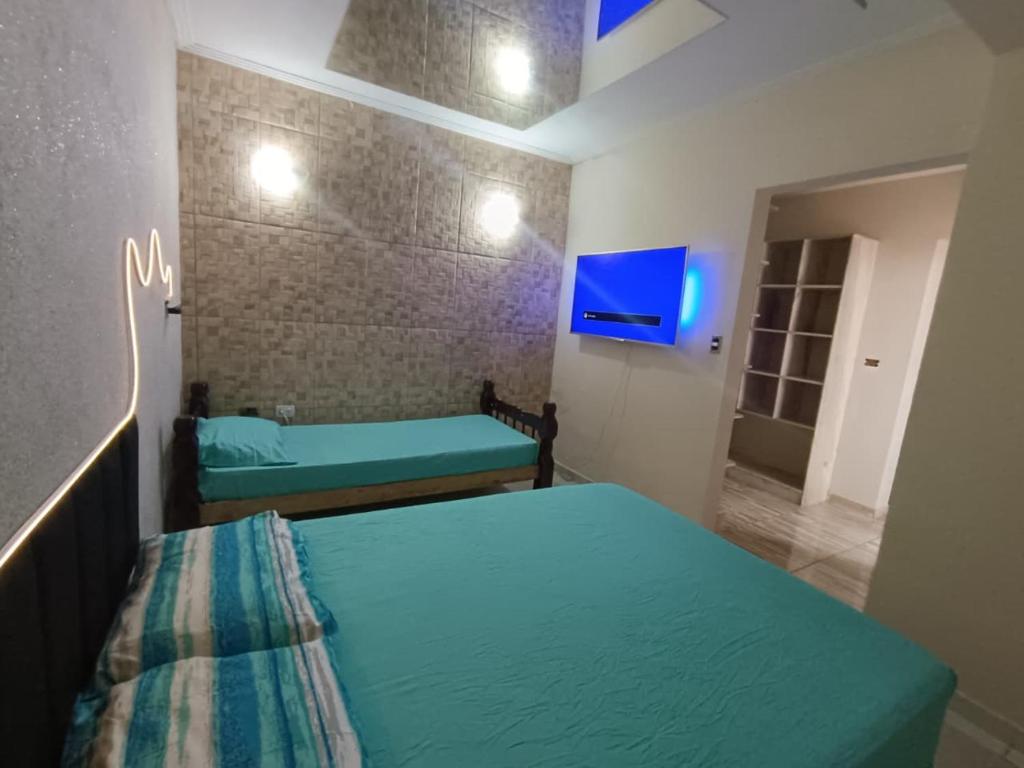 a small room with two beds and a tv at Edícula aconchegante em Peruíbe in Peruíbe