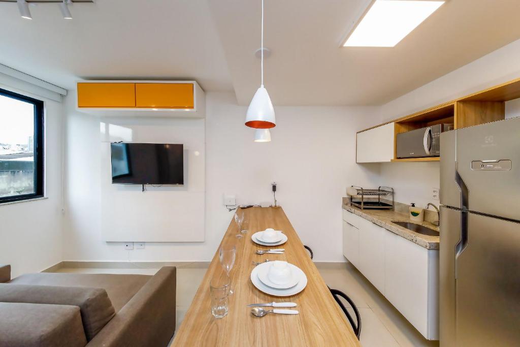 a kitchen and living room with a long wooden table at Studio 404 On São Mateus in Juiz de Fora