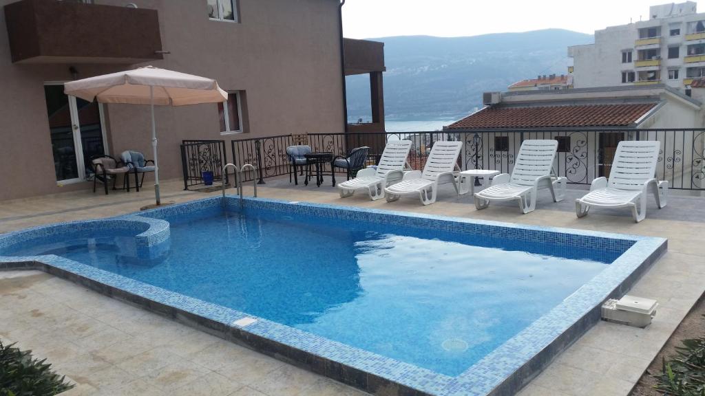 a swimming pool with chairs and an umbrella next to a building at Apartments Lav Costas in Herceg-Novi