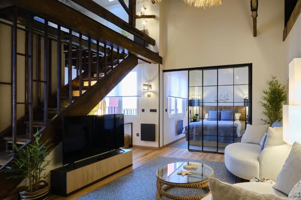 a living room with a couch and a tv and a stair at El Amarre - Apartamento boutique camarote frente a la playa - Grupo Querbes in Gijón