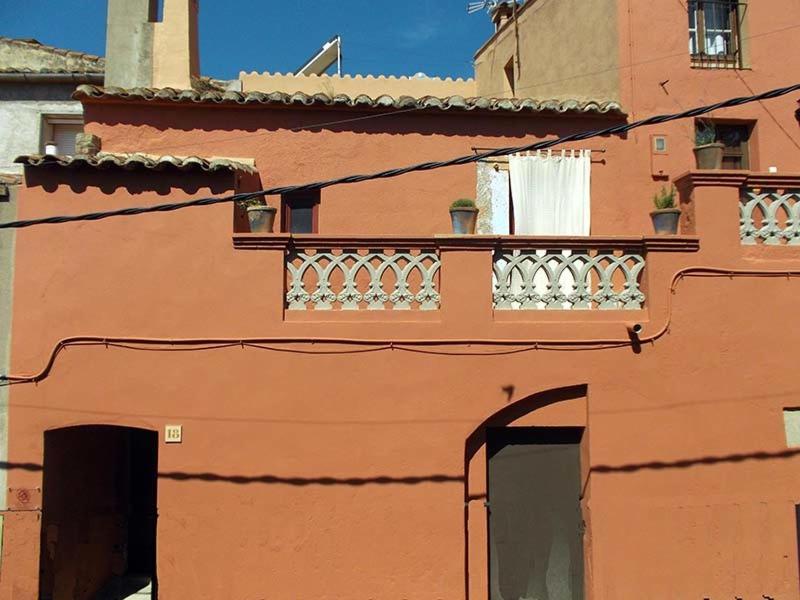 un edificio anaranjado con un balcón en el lateral. en Ca La Marutxi, en Cantallops