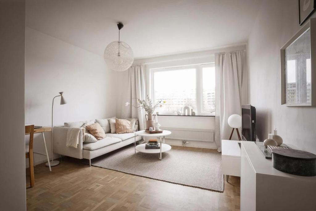 a white living room with a couch and a tv at 2a i Majorna in Gothenburg