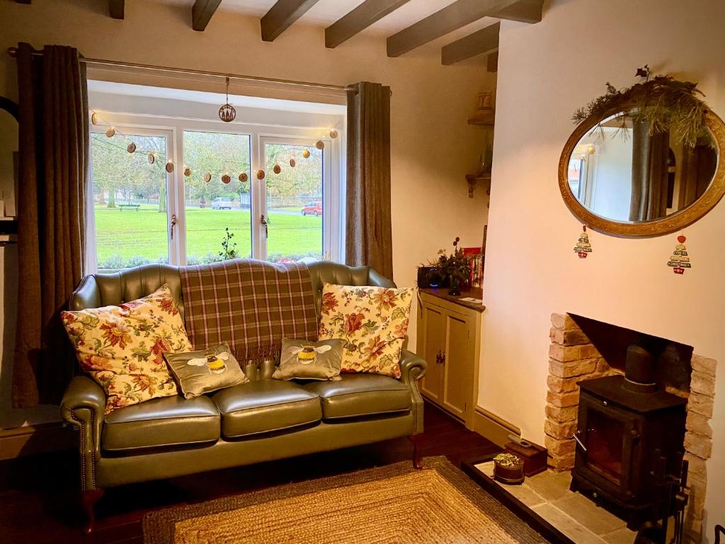 a living room with a leather couch and a fireplace at Relaxing Cottage Escape - Pub - Fire - King Size Bed in Newton Aycliffe
