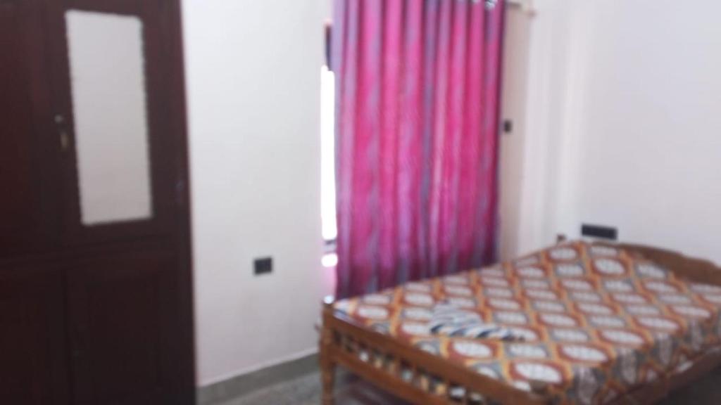 a bedroom with a bed and a red curtain at New royal home stay in Varkala