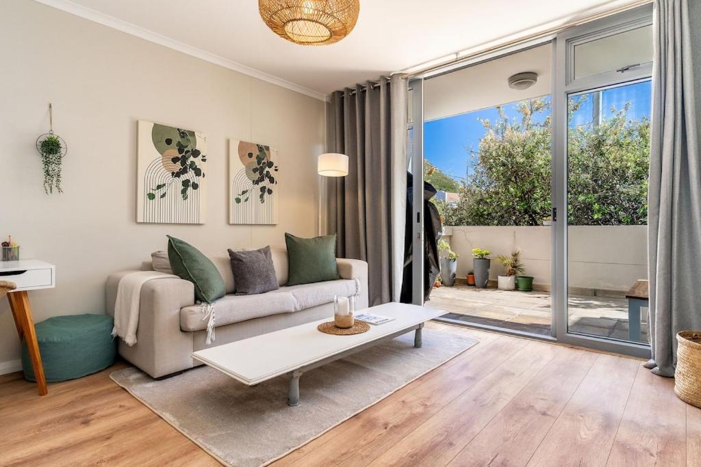 a living room with a couch and a table at Melrose Tide 1 Bed Spacious Apartment in Muizenberg