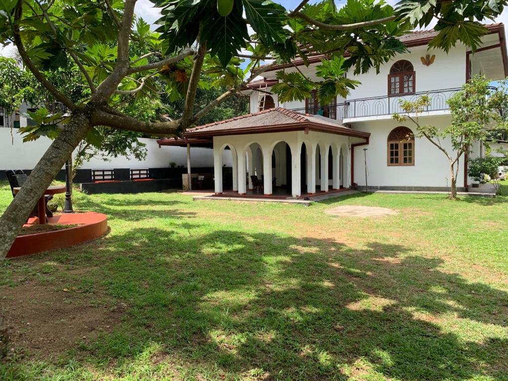 a large white house with a tree in the yard at Casa Bianconera in Colombo