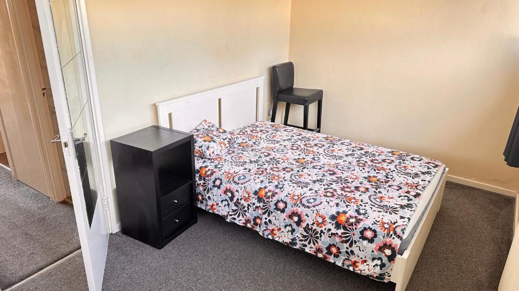1 dormitorio con 1 cama con colcha de flores y silla en Enfield court, en Enfield