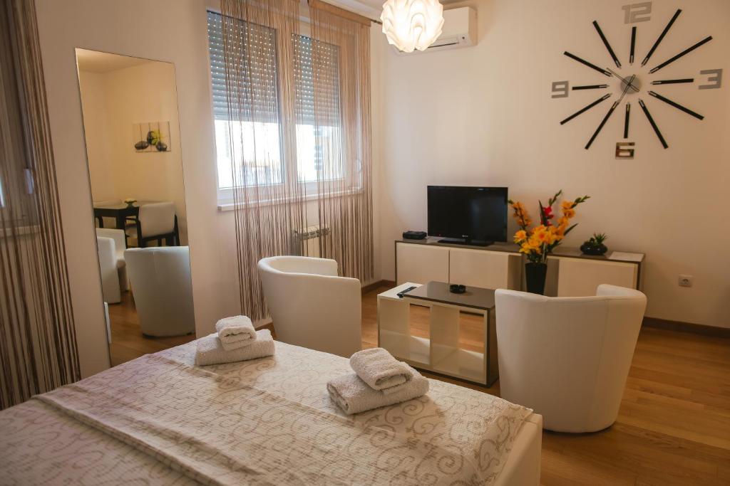 sala de estar con mesa, sillas y reloj en Maja Apartment en Belgrado