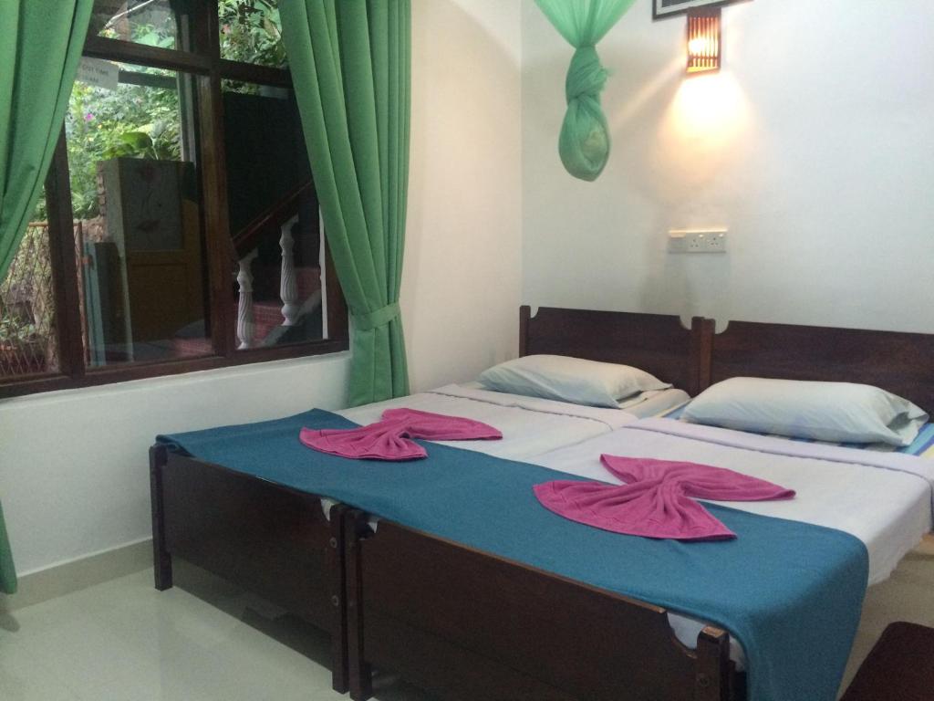 a bedroom with a bed with two pink towels on it at Green Woods in Kandy