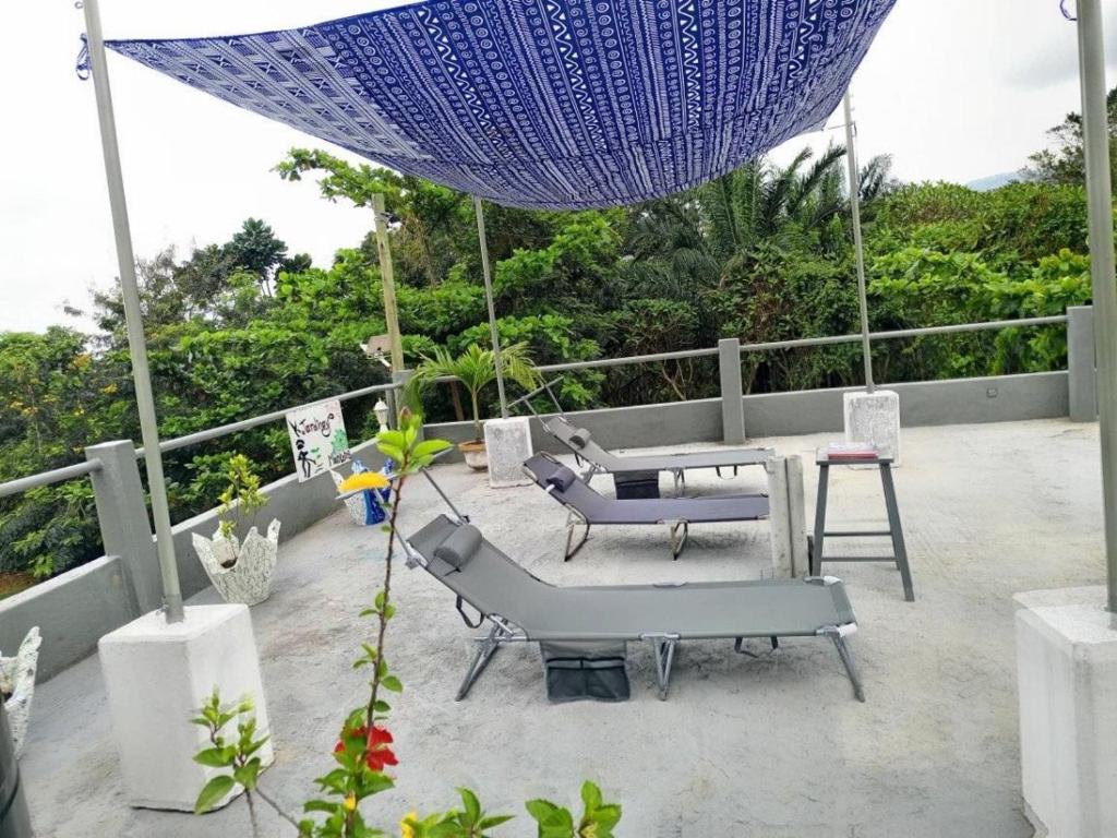 um pátio com um guarda-sol azul, uma mesa e cadeiras em Hotel Eyram Kpalime em Palimé