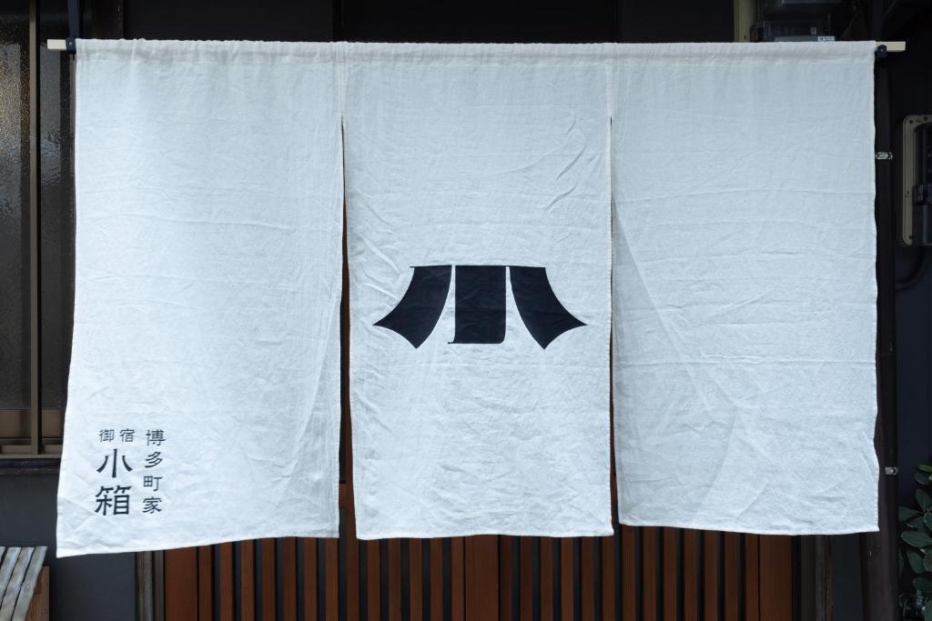 a white towel with a black tie hanging on a wall at 博多町家小箱 in Fukuoka