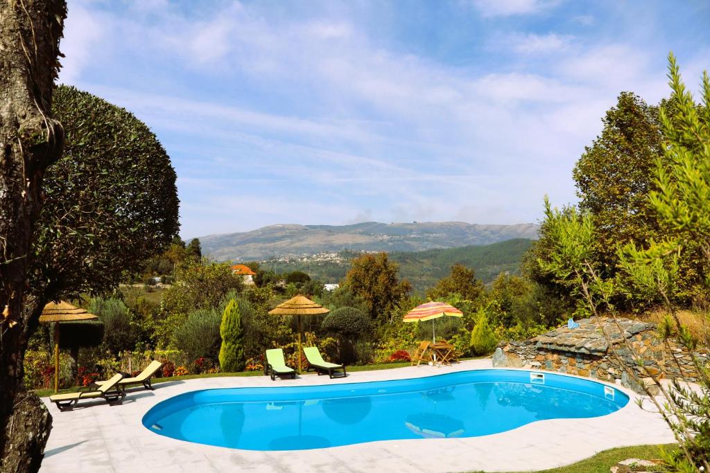 a swimming pool in a yard with chairs and umbrellas at Sonho Verde in Ribeira de Pena