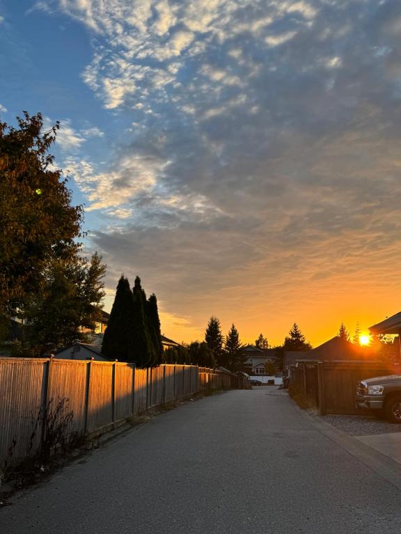 a road with a fence and a sunset in the background at Peaceful House with Backyard in Langley