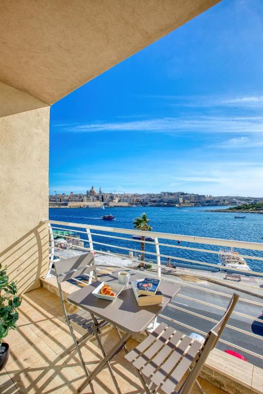 a balcony with a table and chairs and the water at Stunning Seafront Apartment with Panoramic Views in Sliema