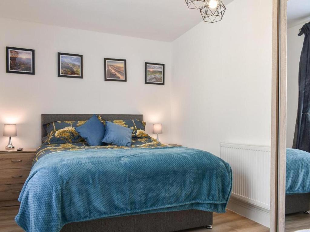 a bedroom with a bed with a blue blanket at Ladybower Apartment Central Glossop in Glossop