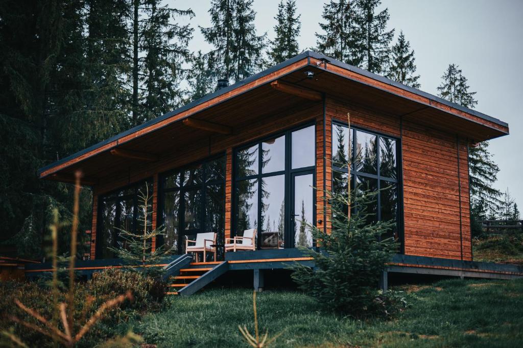 a wooden cabin with a bench in a forest at Inima Pustei Cabin in Măguri