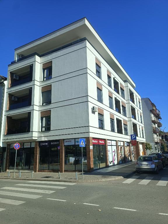 a large white building on a city street with a car at Apartman Markovic Rich in Loznica