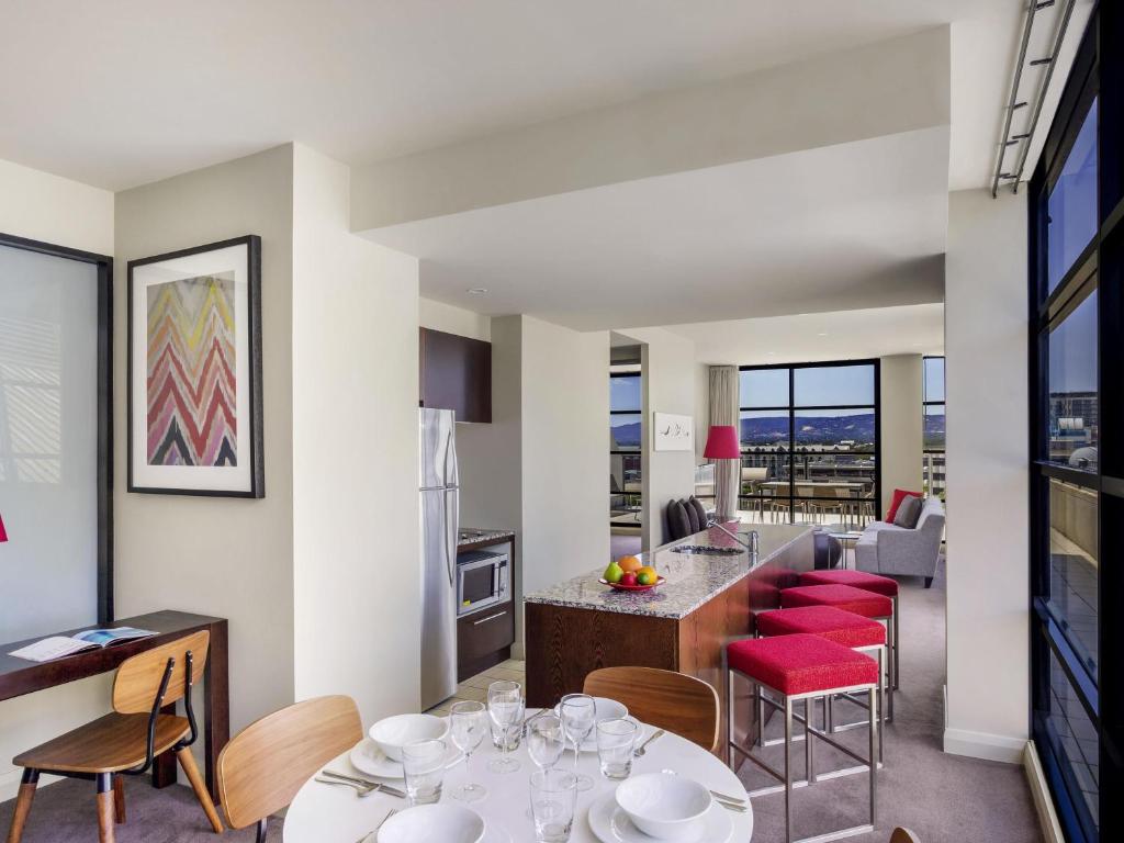 a kitchen and living room with tables and chairs at Mantra Hindmarsh Square in Adelaide