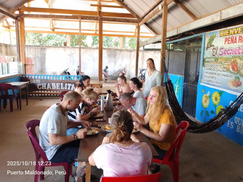 a group of people sitting around a wooden table at Refugio Chabelita Hostel in Puerto Maldonado