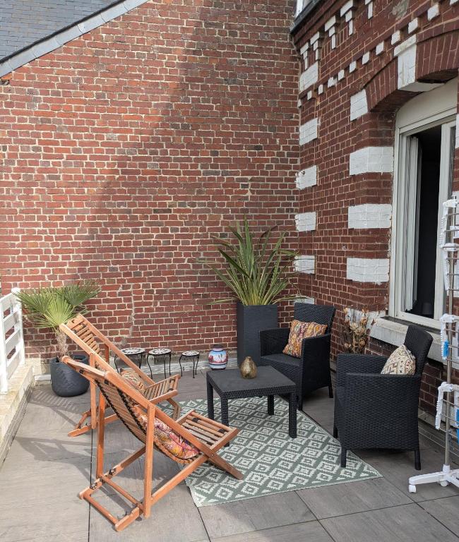 a patio with furniture and a brick wall at Spacieux apt avec terrasse proche plage in Criel-sur-Mer