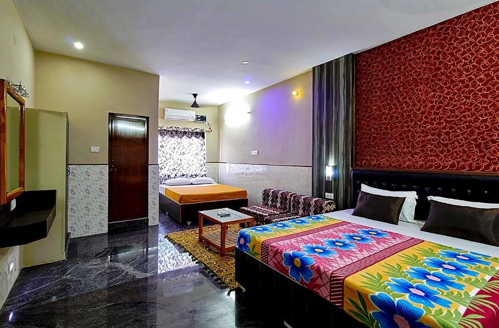 a bedroom with a large bed and a couch at Vinodhara Guest House in Mahabalipuram