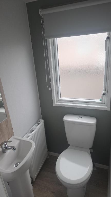 a bathroom with a toilet and a sink and a window at A&l by the sea in Fleetwood