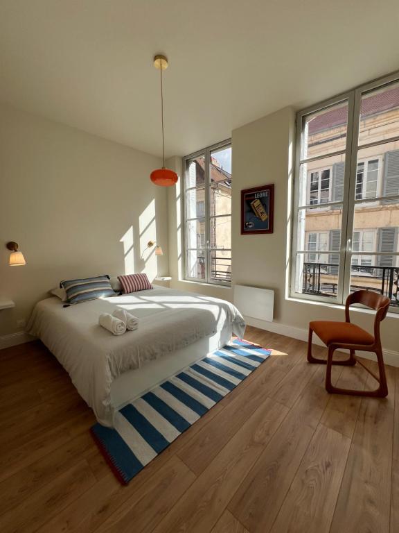 a bedroom with a bed and a chair and windows at Design et Charme en Centre Ville - 2 Chambres Doubles - Parking Public Gratuit in Avallon