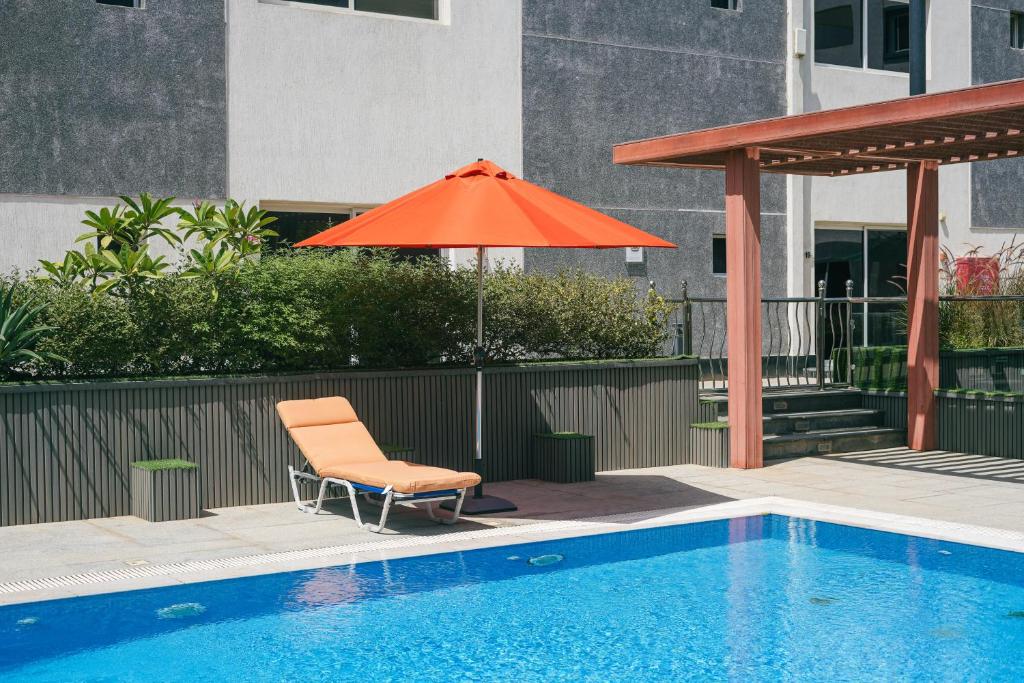 an orange umbrella and a chair next to a pool at Mabaat-White Pearl Compound 600 D Villa 28 in Jeddah