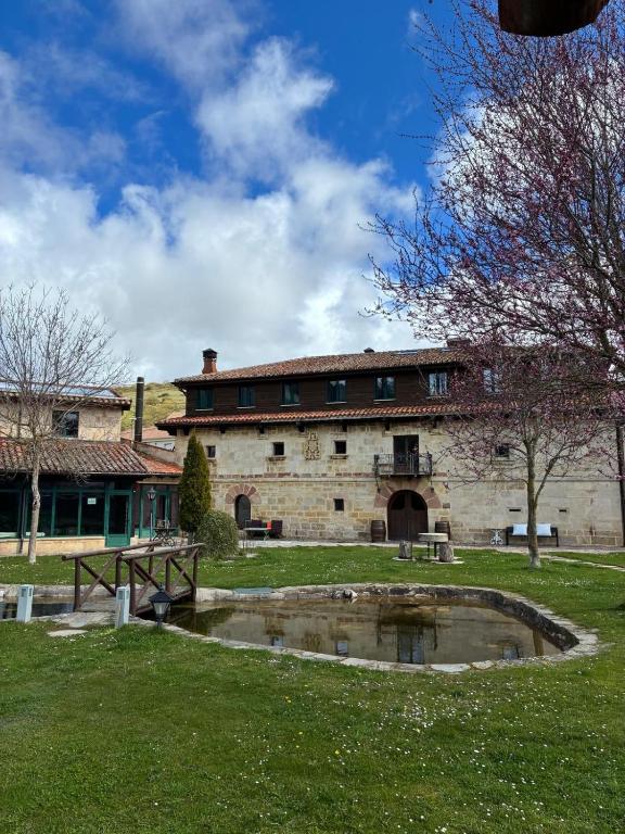 an old building with a pond in front of it at Posada-Finca Fuentes Carrionas in Camasobres