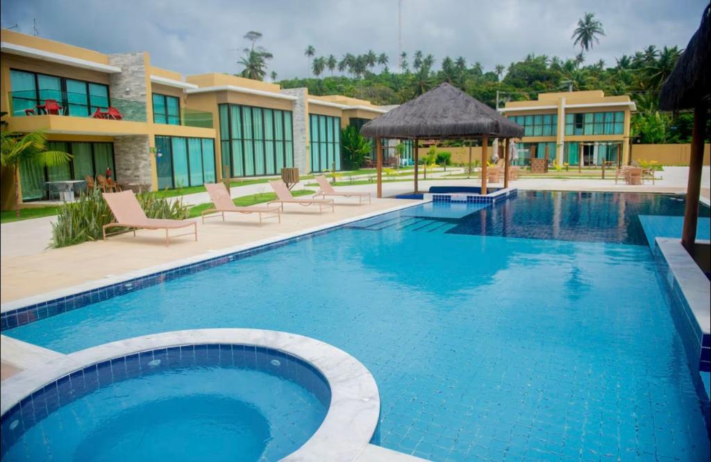 a large swimming pool with chairs and a building at Casa Milagres Morada do toque- By milagres hospitalidade in São Miguel dos Milagres