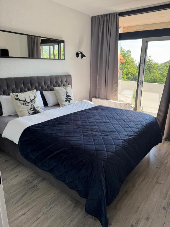 a large bed with a blue comforter in a bedroom at Schöne Aussicht - charmante Ferienwohnung mit Pool und Sauna in Bad Harzburg in Bad Harzburg