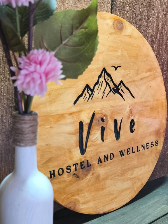 a wooden sign with a vase with a flower at Vive Hostel in Puerto Natales