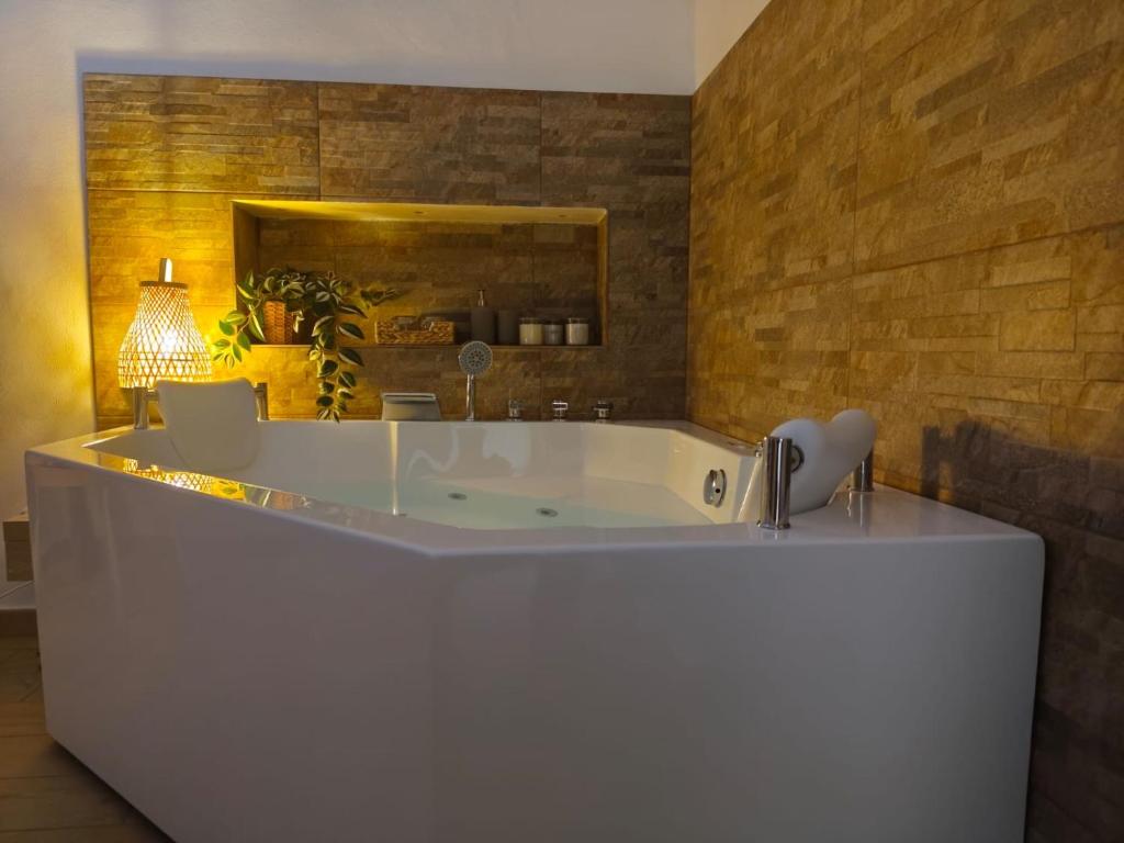 a bath tub in a bathroom with a brick wall at Villa Iliana in Lucca