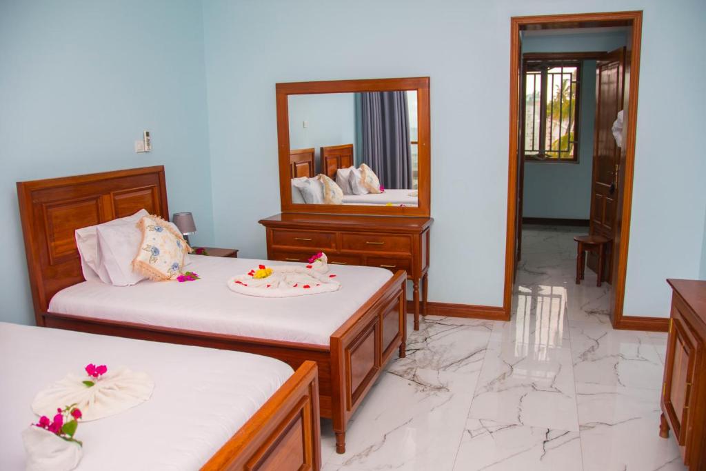 Un dormitorio con dos camas y un espejo. en Zamu Beach Villa, en Pwani Mchangani